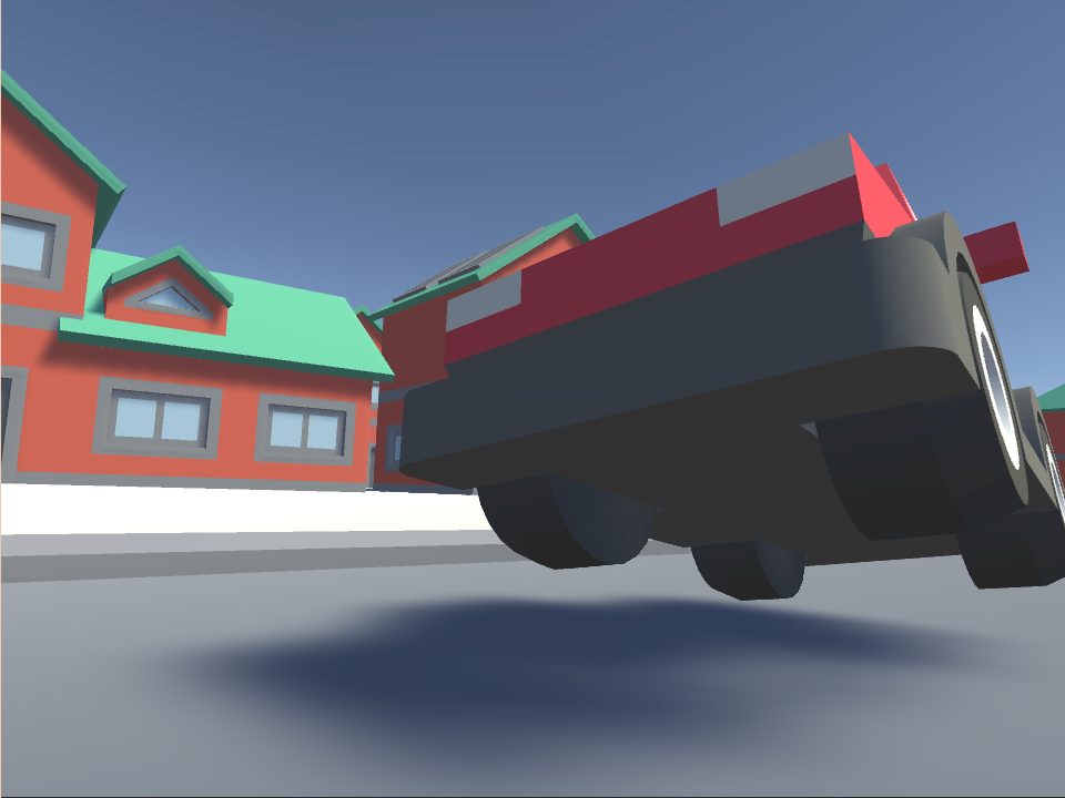 In-game screenshot: a low-poly red truck on a grey road between orange houses with green roofs, seen from behind and below